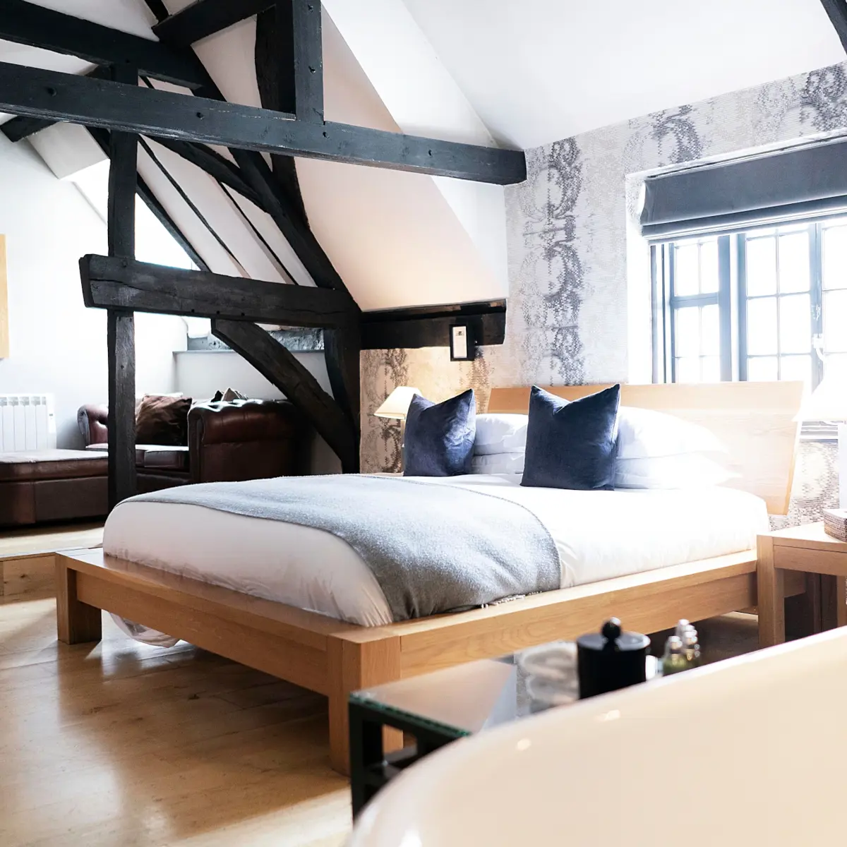 Bed in front of a window with dark wooden beams surrounding 