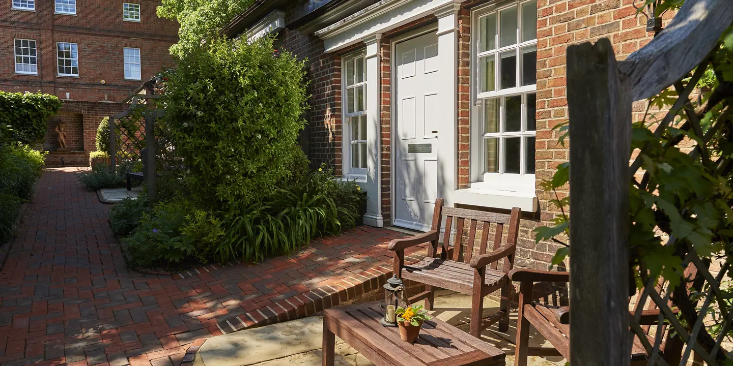 A wooden bench positioned in front of a brick building.