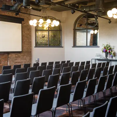 An auditorium with rows of chairs and a large projector screen.