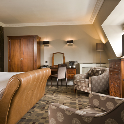 Spacious bedroom featuring a king-sized bed and an elegant chair.