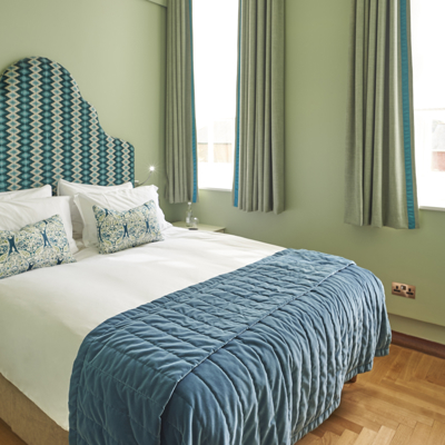 A bed adorned with a stylish blue and white comforter, accompanied by matching pillows.