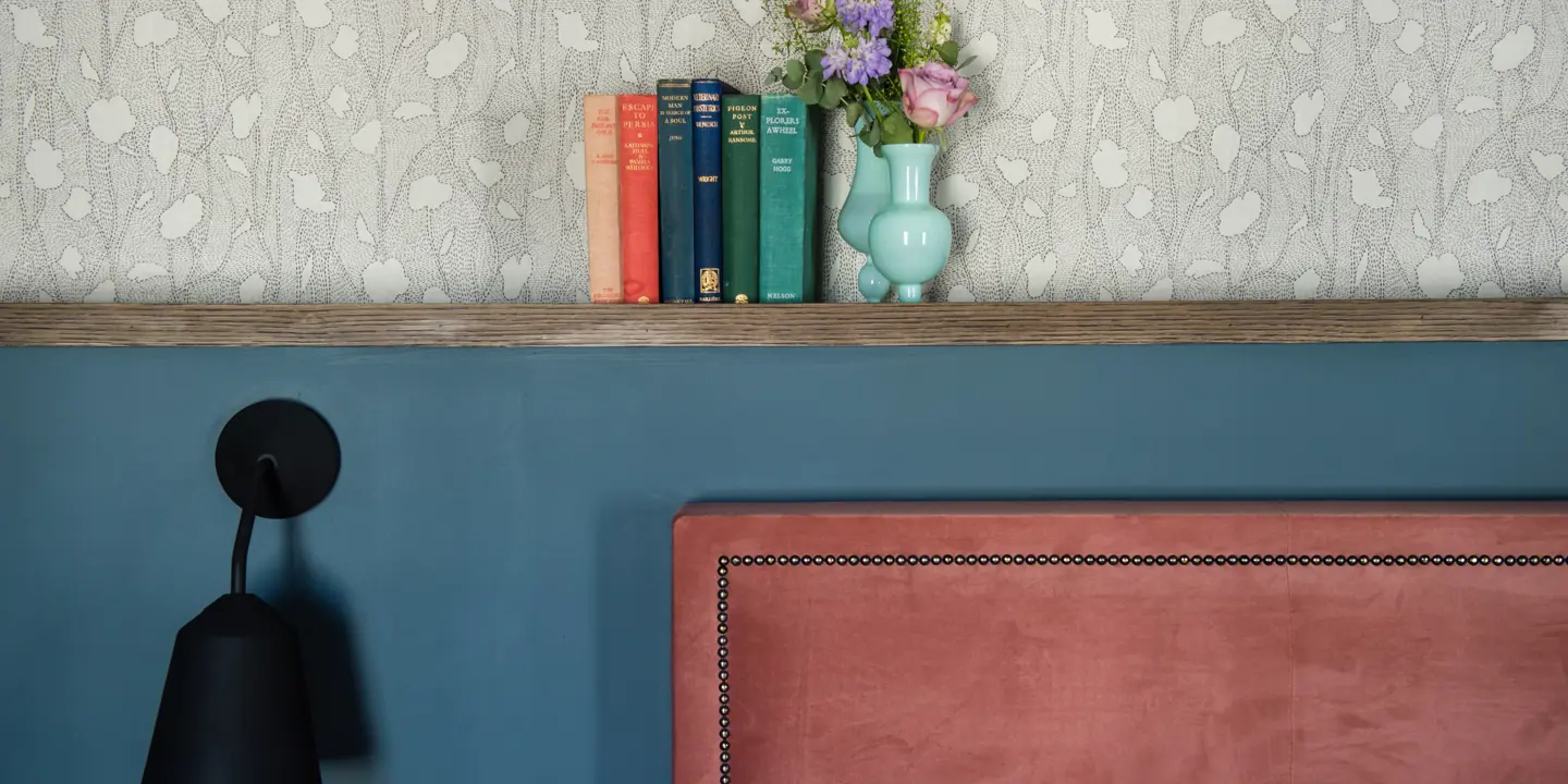 A bookshelf displaying various books with a vase placed on top.