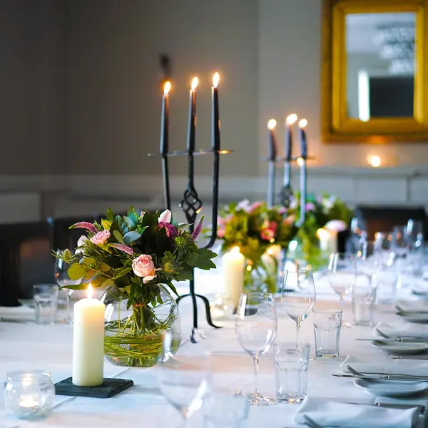 Table elegantly set for a formal dinner, adorned with candles and flowers.