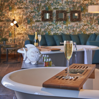 A glass of wine placed on a tray inside a bathtub.