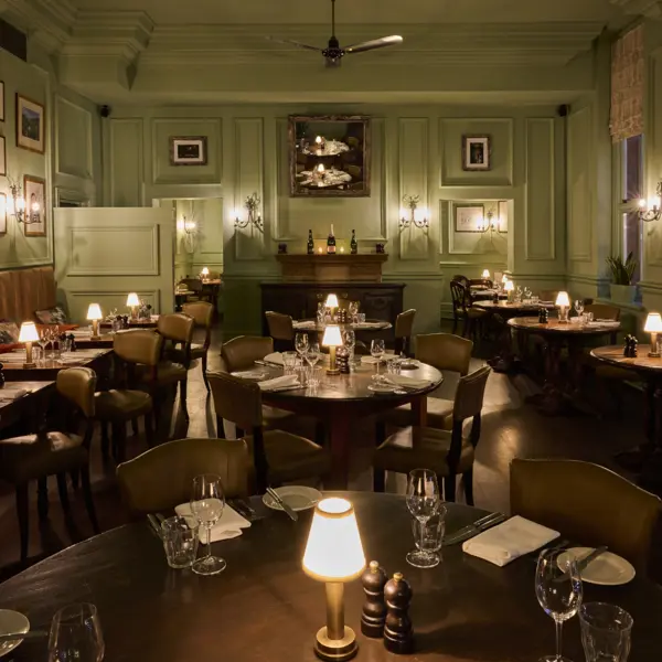 A prepared lowly lit dining hall with wooden tables and chairs