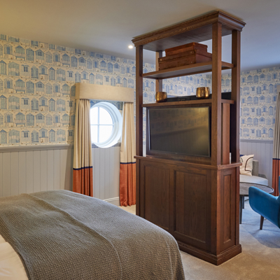 An elegantly furnished bedroom featuring a comfortable bed, a stylish chair, and a modern television.