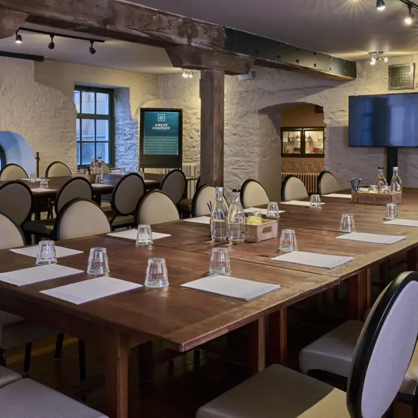 A long wooden table adorned with sleek black chairs and neatly arranged place settings.