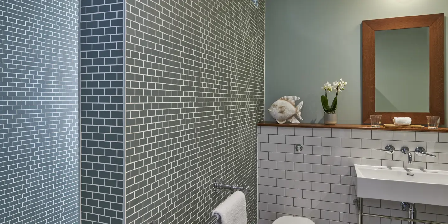 A bathroom featuring a toilet, sink, mirror and fish ornament.