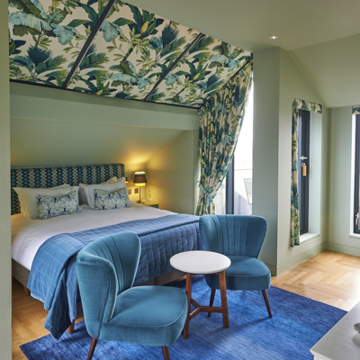 Neatly arranged bedroom with a well-made bed and blue chairs.