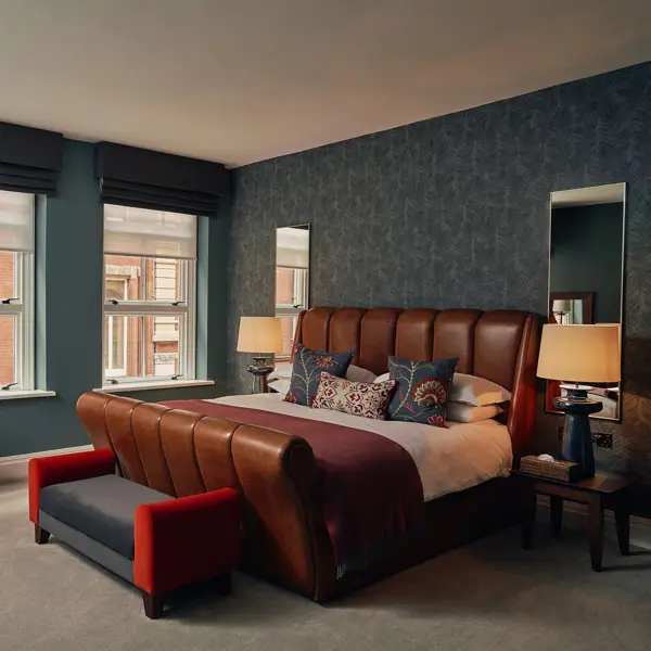 Bedroom featuring a comfortable bed, chair, bedside table, and windows.