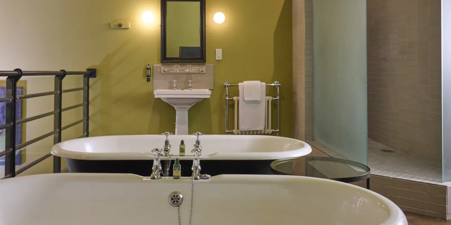 A bathroom featuring a bathtub, sink, and a bottle of wine.