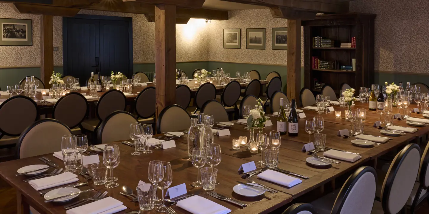 A neatly assorted wooden table with glasses and cutlery placed by each seat