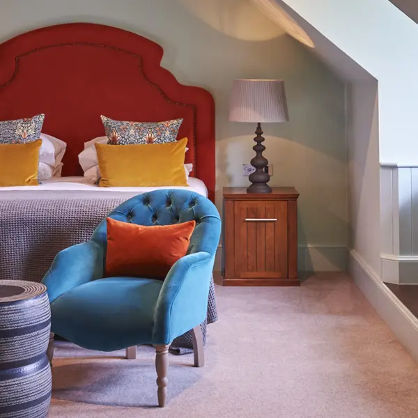A suite decorated in bright colours. There is a bed and a bath in view